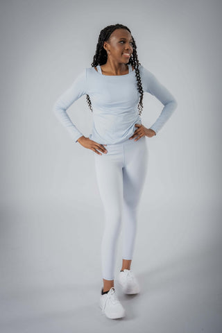 Showcasing the Valentina Ballerina Shirt by Yebo Clothing in a light, airy setting, this sustainable athleisure piece promotes ethical fitness apparel made from recycled materials, perfect for layering or solo wear.